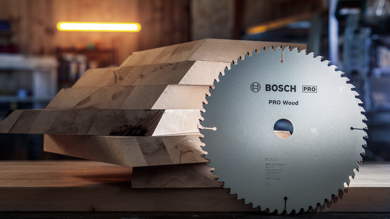Circular saw blade placed beside stacked wooden boards in a workshop.