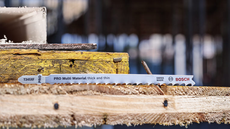 Jigsaw blade rests on stacked wooden planks at a construction site.