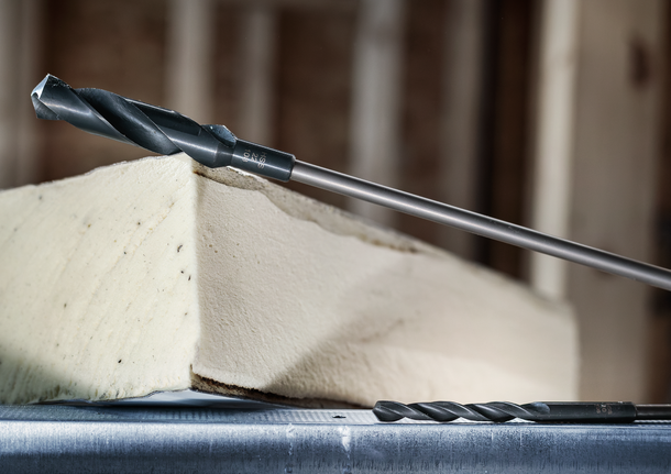 Two drill bits positioned near a block of foam insulation.