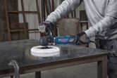 A person wearing safety equipment uses a polisher on a metal surface.