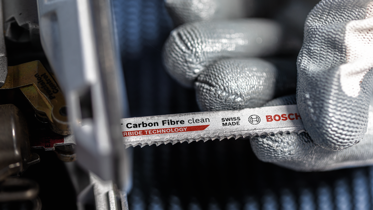 Person wearing safety equipment installs a carbon fiber saw blade into a power tool.