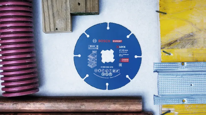 Carbide saw blade placed on a table surrounded by wood, metal, and plastic materials.