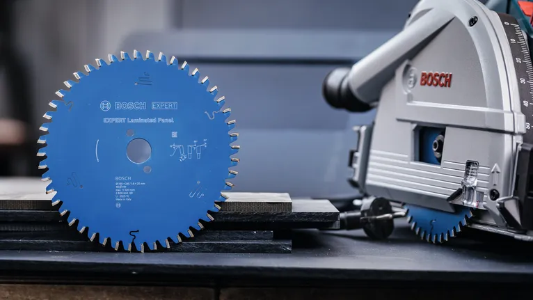 Circular saw blade and power saw placed on a workbench with wooden planks.