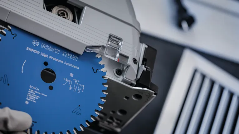 A person wearing safety equipment installs a circular saw blade into a power tool.