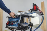 A person adjusts a table saw in a workshop.
