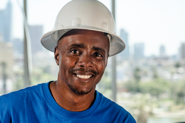 Pessoa que usa equipamento de segurança sorri num canteiro de obras.