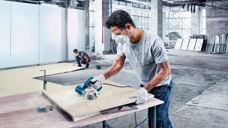 Cortador de azulejos diamantado Bosch GDC 140 em utilização num local de trabalho.