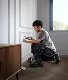 Uma pessoa instala uma tampa de tomada elétrica com uma chave de fendas sem fios.