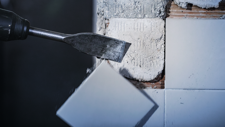 Ferramenta de cinzel a remover um azulejo de cerâmica de uma parede.