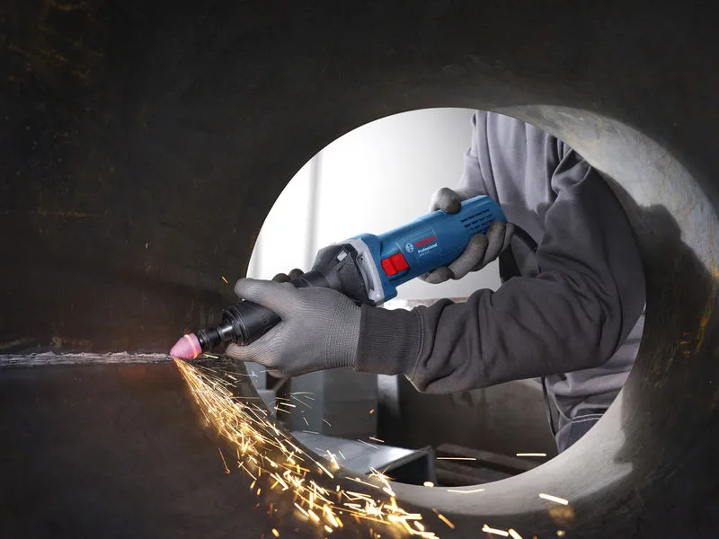 Uma pessoa que usa equipamento de segurança utiliza uma retificadora reta para alisar o interior de um cano de metal.