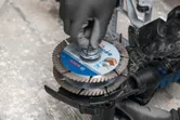 Uma pessoa que utiliza equipamento de segurança instala um disco de corte numa fresadora de parede.