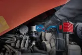 Uma pessoa que utilize equipamento de segurança utiliza uma chave de impacto sem fios num motor.