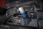 Uma pessoa que utilize equipamento de segurança utiliza uma chave de impacto sem fios em máquinas pesadas.
