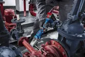 Uma pessoa que utilize equipamento de segurança utiliza uma chave de impacto sem fios em tubagens industriais.