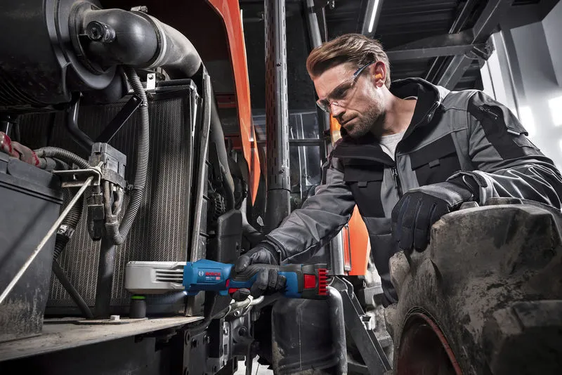 Uma pessoa que utilize equipamento de segurança utiliza uma chave de impacto sem fios para apertar peças em máquinas pesadas.