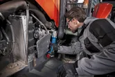 Uma pessoa que utilize equipamento de segurança utiliza uma chave de impacto sem fios em máquinas pesadas.