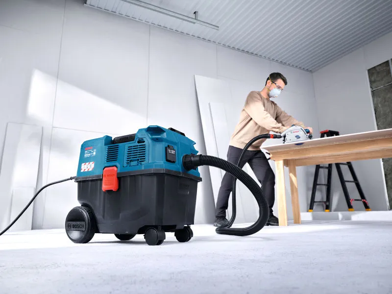 Uma pessoa que utilize equipamento de segurança utiliza um extrator multiusos enquanto corta madeira numa mesa.