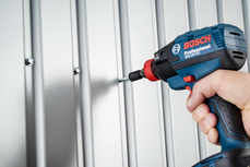 Person drives a screw into a metal panel using a cordless power tool.