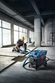A person wearing safety equipment operates an all-purpose extractor on a concrete floor.