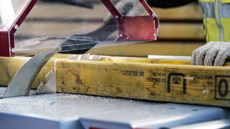 Person wearing safety equipment prepares to cut wood with a circular saw blade.