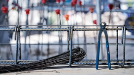 Steel pliers and wire next to a rebar frame at a construction site.