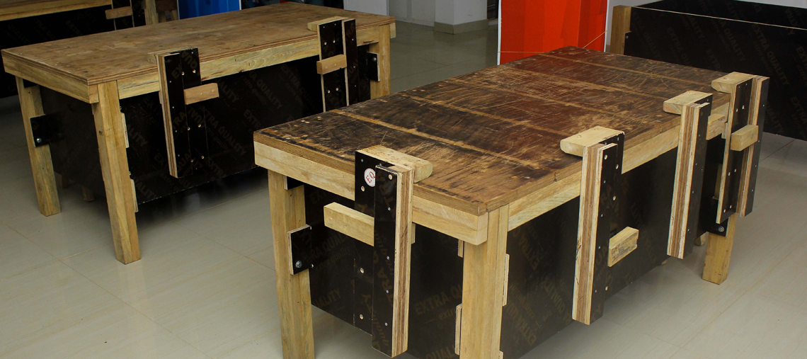 Two wooden workbenches with metal clamps in a bright indoor space.