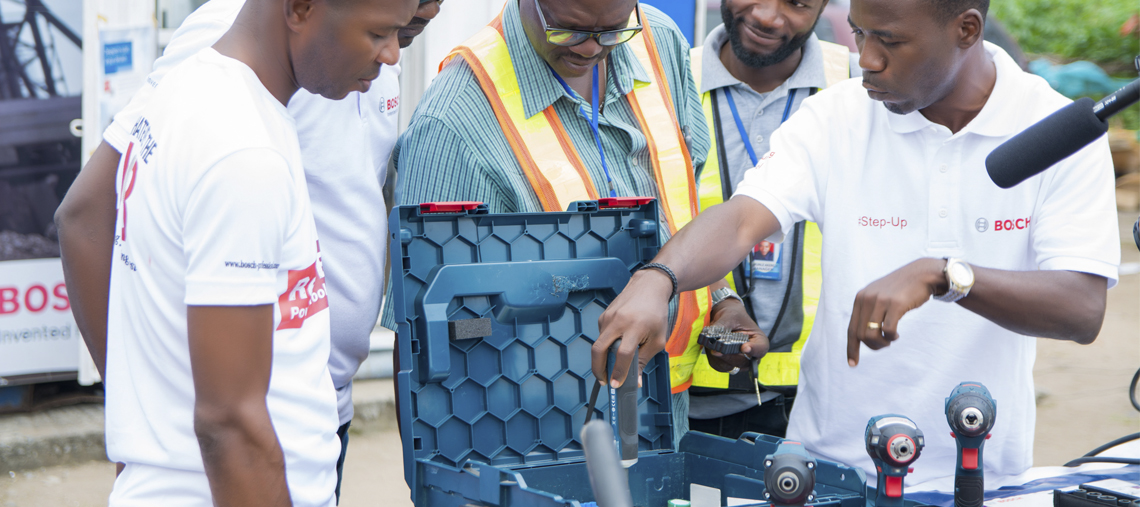Four men discuss Bosch tools at a training event, showcasing drills and accessories.