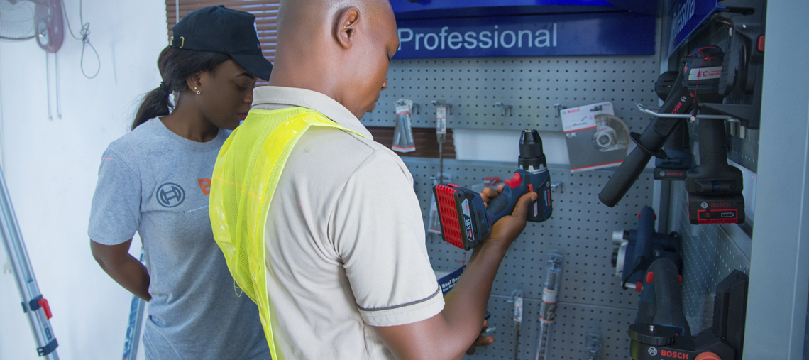 A man inspects a Bosch Professional drill while a woman observes nearby in a tool store.