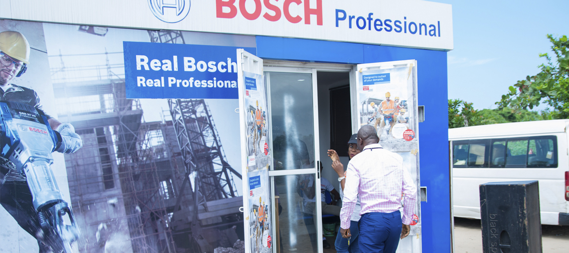Bosch Professional store entrance with two people interacting outside in bright daylight.