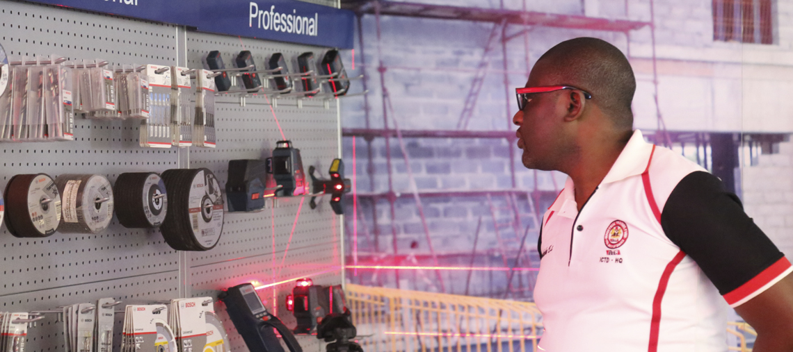 A man examines Bosch Professional tools on a display wall, focused and engaged.