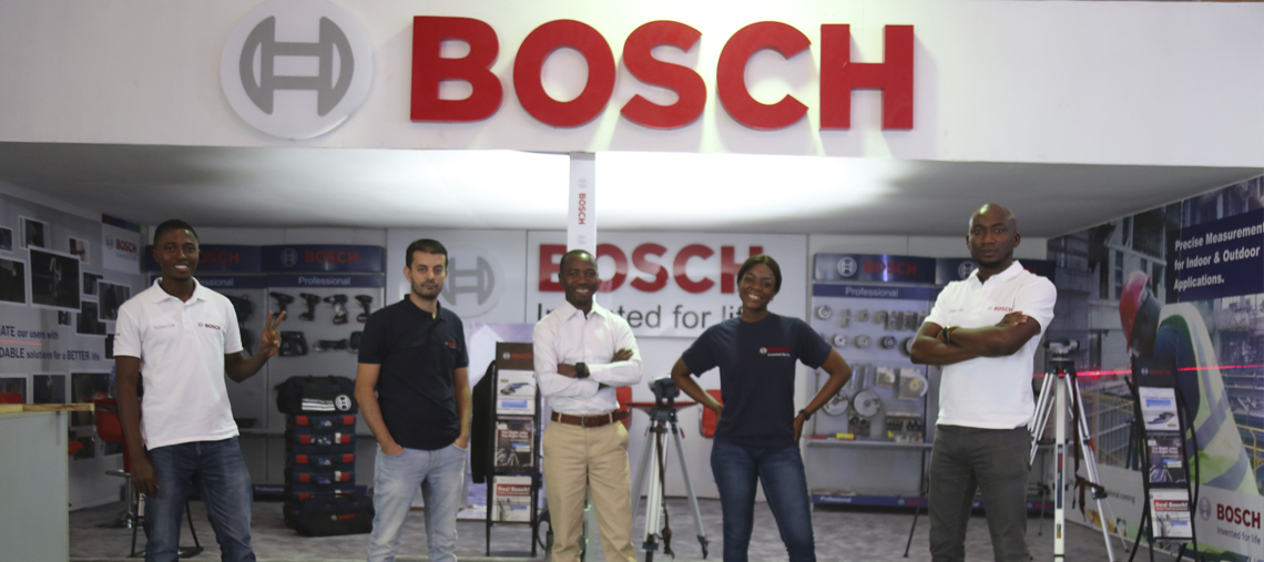 Five Bosch employees stand in a showroom with tools and a large Bosch sign behind them.