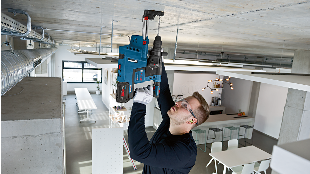 Een man gebruikt een Bosch Professional gereedschap aan het plafond van een modern kantoor.