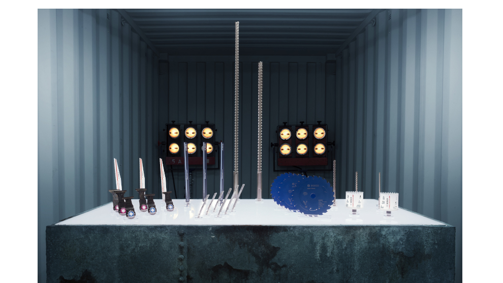 Bosch Professional gereedschap op een witte tafel in een container, met boren en zaagbladen.