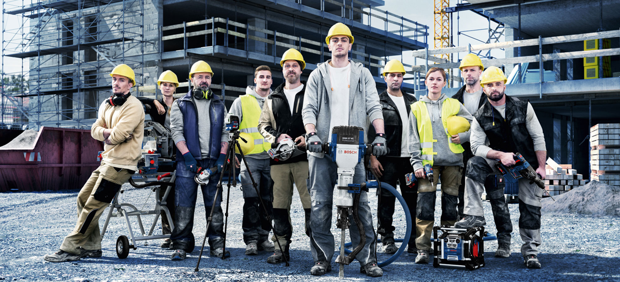 Een groep arbeiders op de bouwplaats met gele helmen en Bosch-gereedschap.