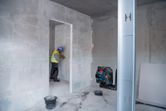 Een persoon met veiligheidsuitrusting markeert een muur met behulp van een groene laserwaterpas.