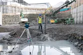 Een persoon die veiligheidsuitrusting draagt, gebruikt een laserwaterpas op een bouwterrein.