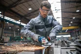 In een industriële werkplaats slijpt een persoon met veiligheidsuitrusting metaal, waarbij vonken ontstaan.