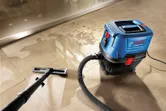 Nat- en droogzuiger die water van een tegelvloer opzuigt.