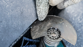 Een persoon met veiligheidsuitrusting zaagt beton met een haakse slijper.