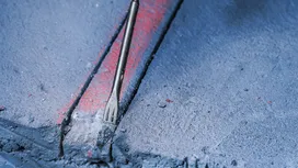 Beitel die beton breekt langs een gemarkeerde rode richtlijn.