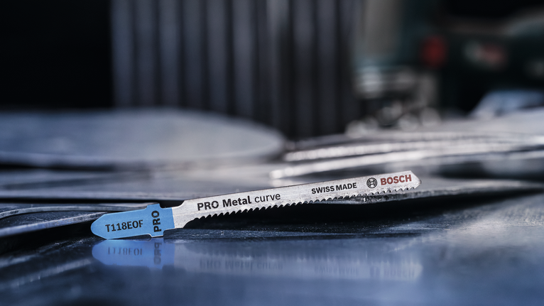 Een metaalzaagblad ligt op gestapelde metalen platen in een werkplaats.