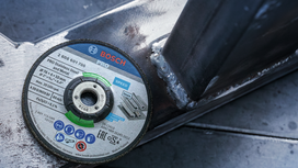 Een slijpschijf ligt naast gelaste metalen balken in een werkplaats.