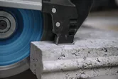 Grote haakse slijper die door een dikke betonplaat slijpt.