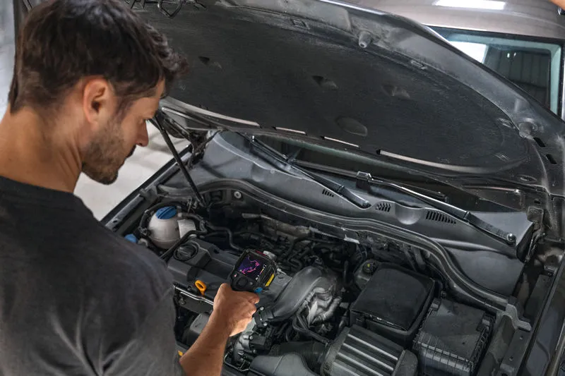 Iemand inspecteert een automotor met behulp van een warmtebeeldcamera.
