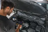 Iemand inspecteert een automotor met behulp van een warmtebeeldcamera.