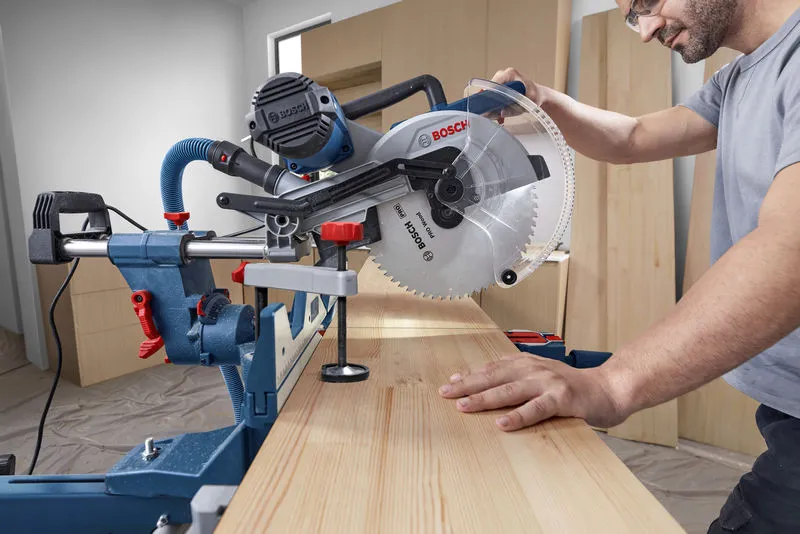 Iemand bedient een verstekzaag om een houten plank te zagen in een werkplaats.
