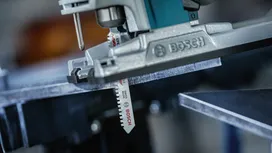 Een decoupeerzaag die een metalen plaat doorsnijdt in een werkplaats.