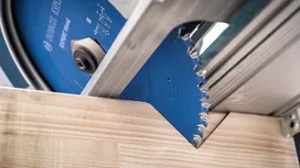 Cirkelzaagblad waarmee een houten plank wordt doorgezaagd.