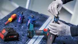 Een persoon die veiligheidsuitrusting draagt, bevestigt een boor aan een snoerloos elektrisch gereedschap.