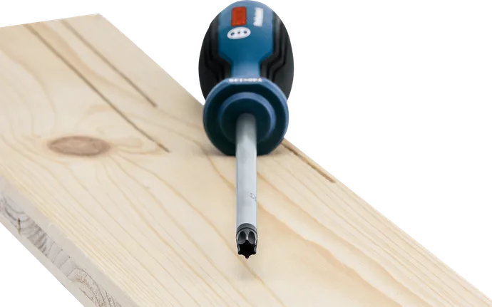 Een schroevendraaier met een speciale punt, rustend op een lichte houten plank.